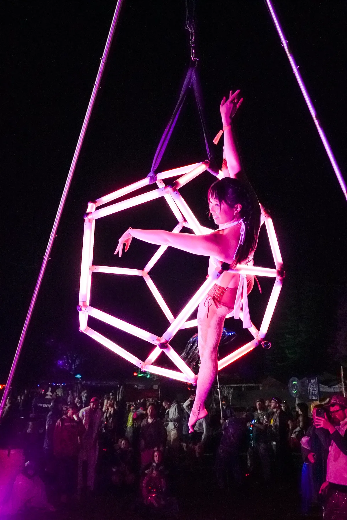 Two people climbing and sitting on the LED dodecahedron at a night festival