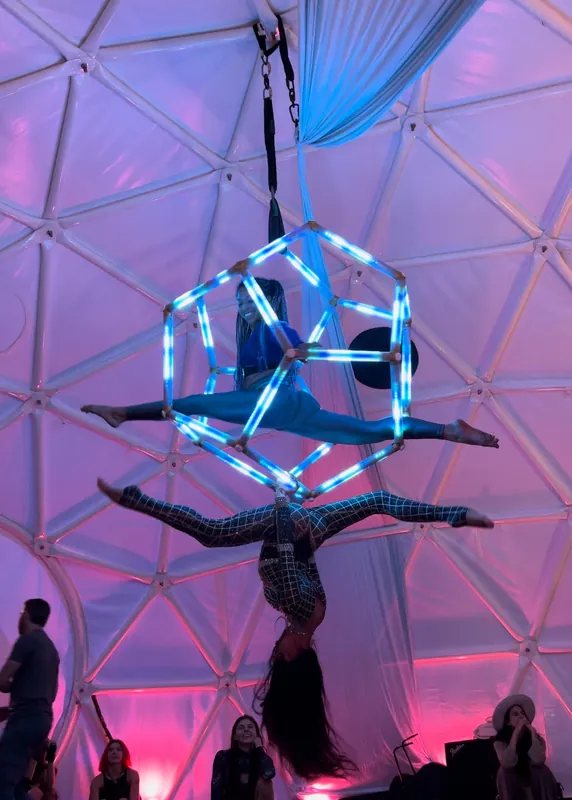 Two aerialists performing a duo act on the blue-lit dodecahedron