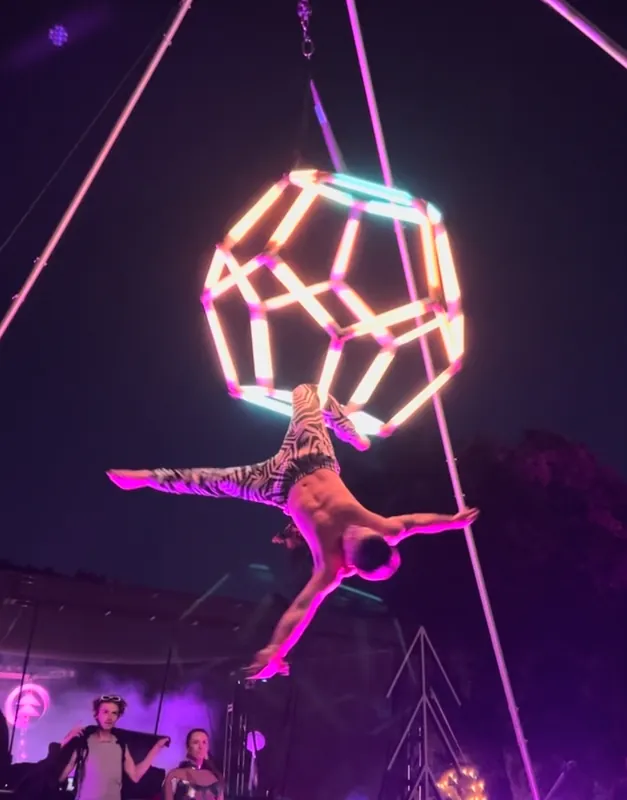 Aerialist performing a one-arm hold from the glowing dodecahedron