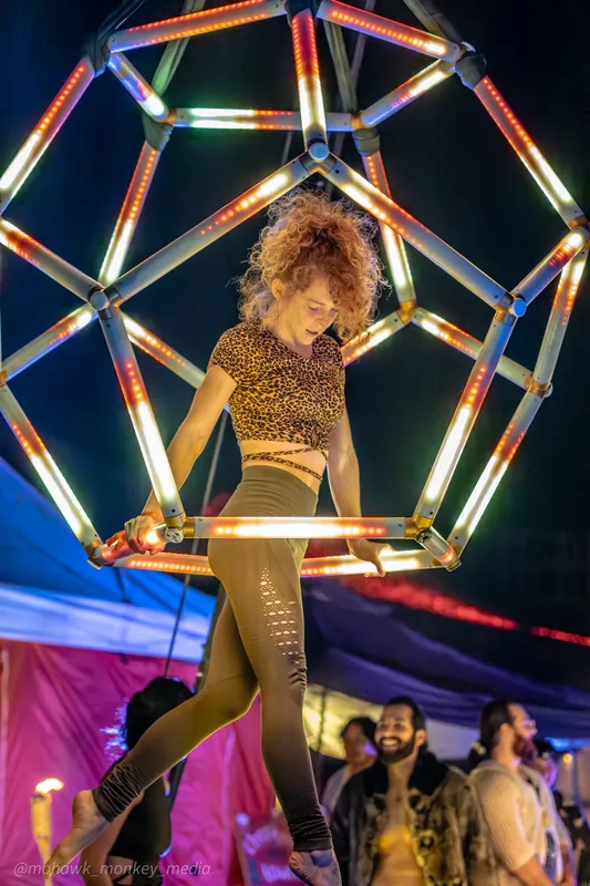 Performer standing inside the warm-lit dodecahedron at a festival