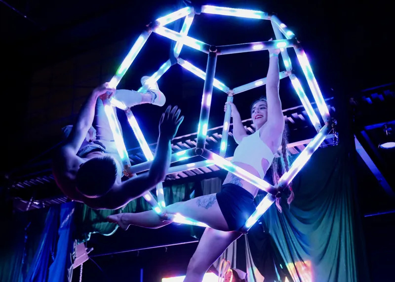 Two aerialists hanging from the LED dodecahedron during an indoor performance