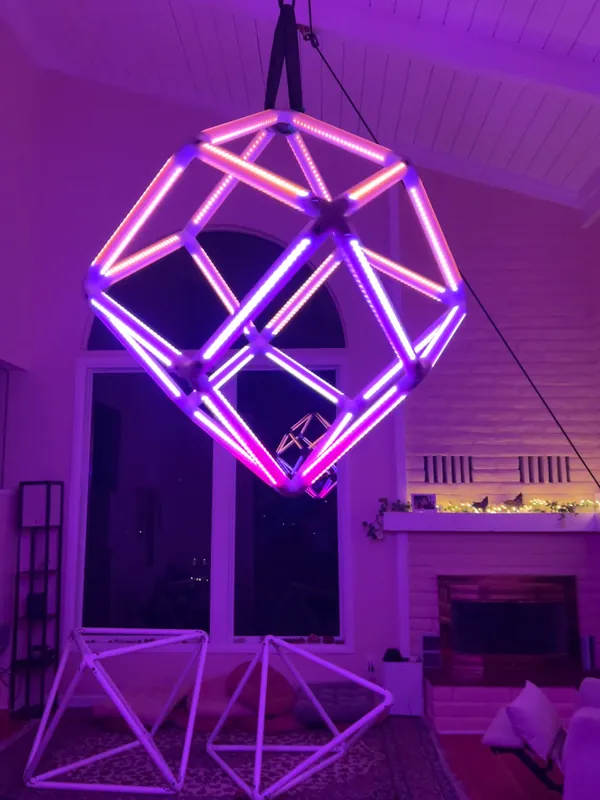 LED dodecahedron and smaller geometric structure glowing purple in a living room