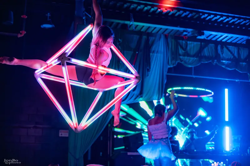 Performer in a diamond-shaped LED aerial structure on stage